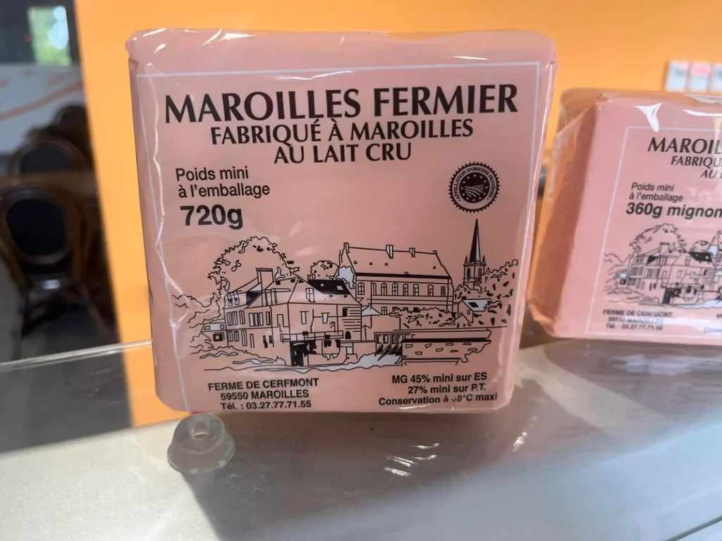 le mythique fromage Maroille, fabriqué à la ferme Montcerf à maroilles dans le nord, c'est un fromage fermeier au lait cru, 2 fromages sont présentés un de 720g et un autre de 360g dans un emballage rose, avec un dessin de la ferme dessus